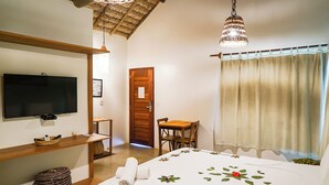 A bedroom with a bed, a television, a wooden door, a table, and a chair.