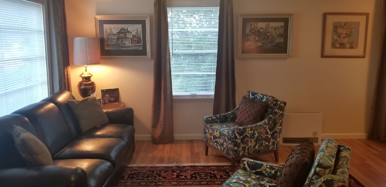 A living room with a leather sofa, a patterned armchair, and a small table with a lamp.
