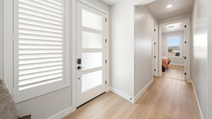 A hallway with white doors, a bed in the distance, and a view of the outdoors. - Isle B there 4U- Private Hot Tub|ResortPool|GolfCourse|Sleeps20 Mins to Canyon (Washington)