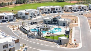 A modern residential complex with a central swimming pool, multiple garages, and a golf course in the background. - Isle B there 4U- Private Hot Tub|ResortPool|GolfCourse|Sleeps20 Mins to Canyon (Washington)