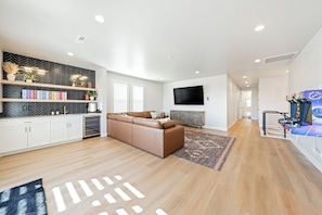 A modern living room with a sofa, TV, and a herringbone-patterned wall. - Isle B there 4U- Private Hot Tub|ResortPool|GolfCourse|Sleeps20 Mins to Canyon (Washington)