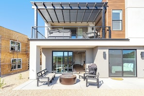 A modern two-story house with a balcony, a patio with outdoor furniture, and a sliding glass door leading to an interior space. - Isle B there 4U- Private Hot Tub|ResortPool|GolfCourse|Sleeps20 Mins to Canyon (Washington)