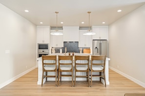 A modern kitchen with white cabinetry, a central island with bar stools, and stainless steel appliances. - Isle B there 4U- Private Hot Tub|ResortPool|GolfCourse|Sleeps20 Mins to Canyon (Washington)