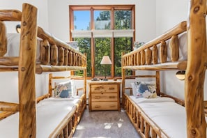 A room with two bunk beds, a wooden desk, and a window with a view of trees. - Ski-in/ski-out Beaver Creek with Hot Tub & Pool (Beaver Creek)