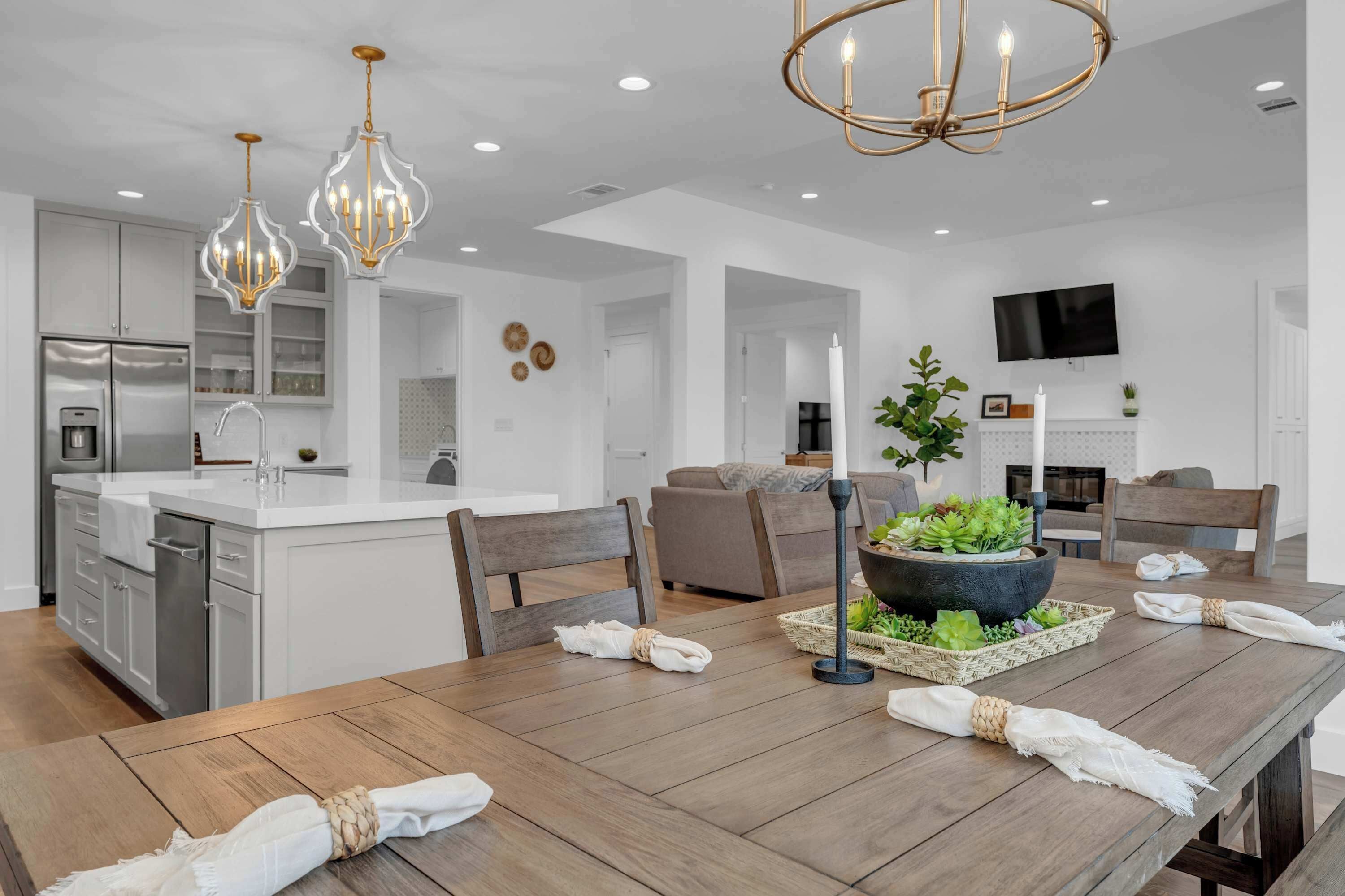 Une cuisine moderne avec des meubles blancs, un îlot central et des luminaires suspendus.