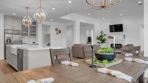 A modern kitchen with white cabinets, a central island, and pendant lighting.