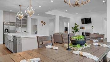 Une cuisine moderne avec des meubles blancs, un îlot central et des luminaires suspendus.