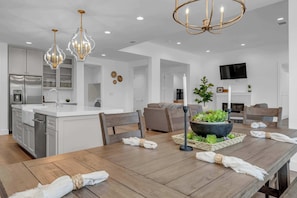 A modern kitchen with white cabinets, a central island, and pendant lighting.