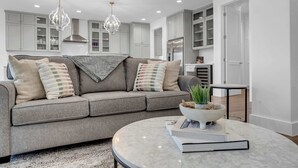 A modern living room with a grey sofa, a marble coffee table, and pendant lights.