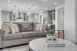A modern living room with a grey sofa, a marble coffee table, and pendant lights.
