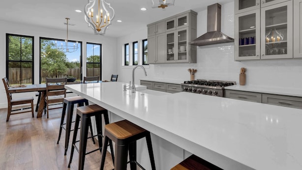 A modern kitchen with a large island, bar stools, and a gas stove.