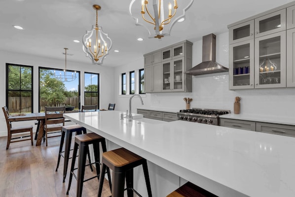 A modern kitchen with a large island, bar stools, and a gas stove.