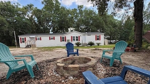 Uma casa com lareira e cadeiras Adirondack no quintal.