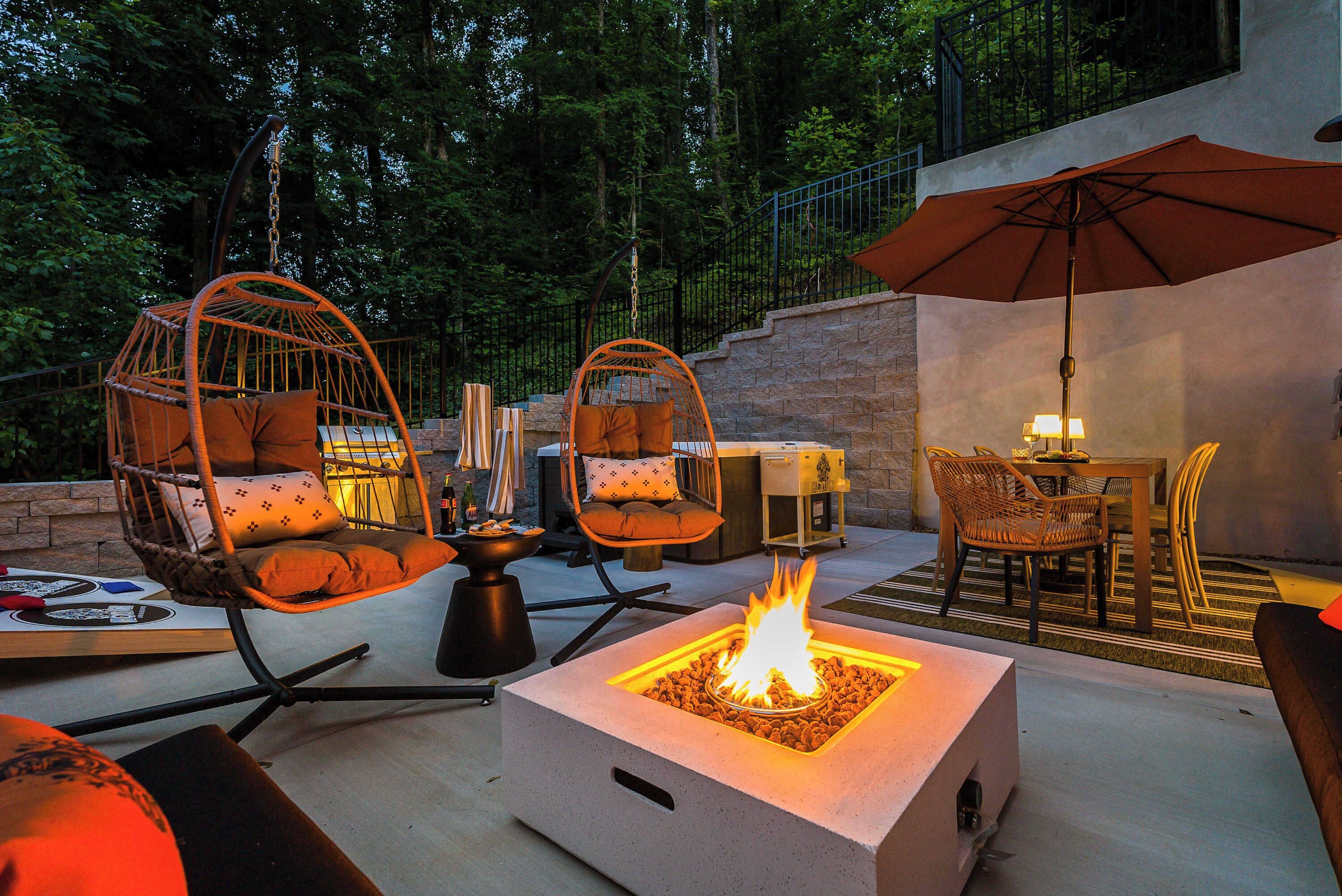 Un patio al aire libre con sillas de mimbre, una chimenea y una zona de comedor con mesa y sillas.