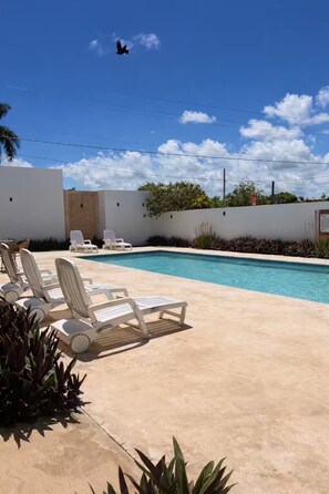 Une piscine avec des chaises longues et un ciel dégagé.
