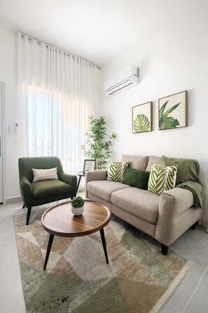 Ein Wohnzimmer mit einer Couch, einem Sessel, einem Couchtisch und einer Topfpflanze.