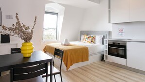 Una moderna camera d'albergo con un letto, un tavolo da pranzo con sedie, un angolo cottura e una finestra vista.