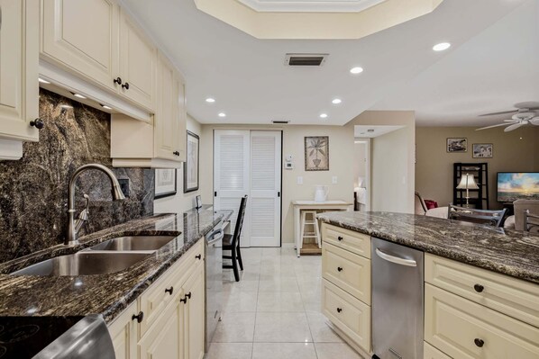 A modern kitchen with granite countertops, stainless steel appliances, and a central island. - 21 Sea Club Condo Near Beach (Indian Shores)