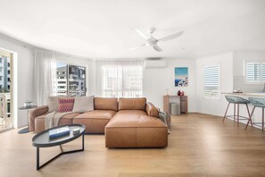 Ein modernes Wohnzimmer mit Ledersofa, Couchtisch und Essbereich mit Barhocker.