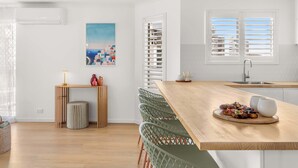 Een moderne keuken met een houten kookeiland, witte keukenkastjes en uitzicht op de stad door de zonwering.