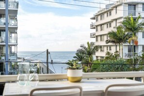 Ein Balkon mit Meerblick, einem Blumentopf und einem Tisch mit Stühlen.