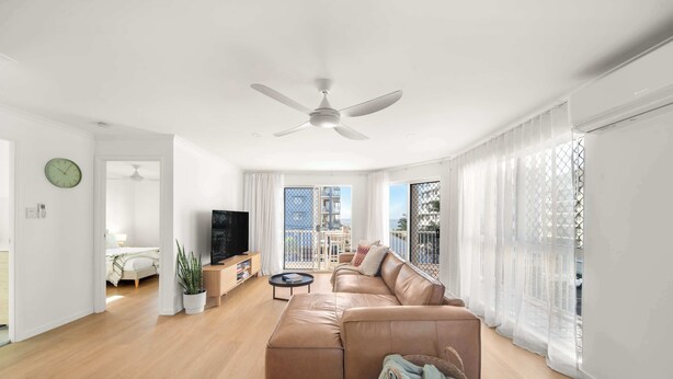 Een moderne woonkamer met een grote bank, een televisie en een balkon met uitzicht.