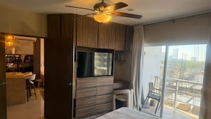 A modern hotel room with a bed, a TV, a balcony with a view, and a kitchenette. - Luxury Apartment 40 m from the Beach and Bike Path (Mazatlán)