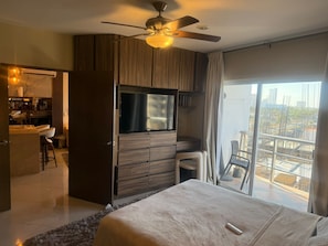 A modern hotel room with a bed, a TV, a balcony with a view, and a kitchenette. - Luxury Apartment 40 m from the Beach and Bike Path (Mazatlán)