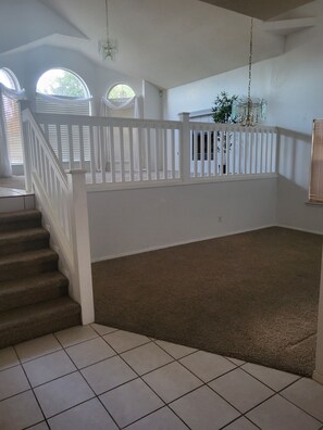 A spacious room with a staircase, a chandelier, and a view through a window. - Cozy 1-bedroom For rent in awesome El Paso with AC (El Paso)