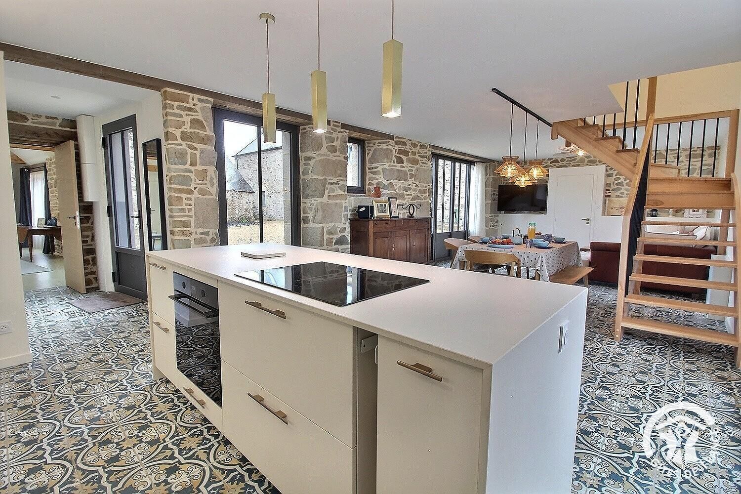 A modern kitchen with a central island, stone walls, and a patterned floor.
