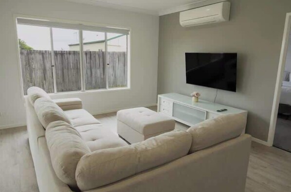 A living room with a sofa, a television, and a window.