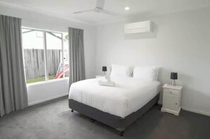 A bedroom with a bed, bedside tables, a ceiling fan, and a window with curtains.