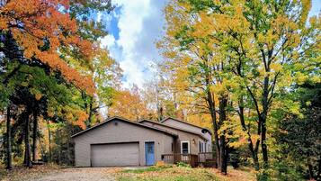 Una casetta a un piano con garage, immersa tra alberi dai colori autunnali.