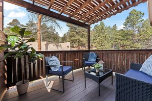 Eine überdachte Terrasse im Freien mit Sitzgelegenheiten, einem Tisch und einem Blumentopf.