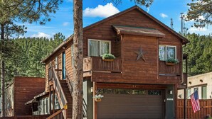 Eine zweistöckige Holzhütte mit Garage, einem Balkon mit Pflanzen und einer Flagge.