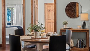 Ein Essbereich mit Holztisch, Stühlen, einem Blumentopf, einer Kerze und einem Spiegel an der Wand.