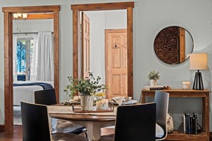 Ein Essbereich mit Holztisch, Stühlen, einem Blumentopf, einer Kerze und einem Spiegel an der Wand.