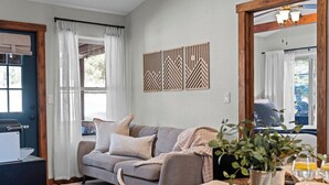 Ein Wohnzimmer mit einer Couch, einem Couchtisch, einer Zimmerpflanze und einem Spiegel, der den Raum widerspiegelt.