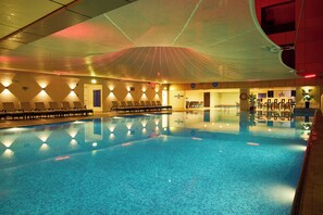 Ein Pool mit Liegestühlen und einer überdachten Liegefläche.