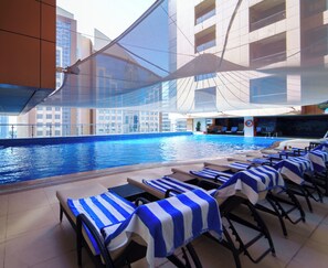 Zona de piscina con sillones de descanso y una alberca.