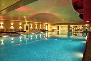 Ein Pool mit Liegestühlen und einer überdachten Liegefläche.