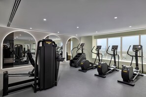Ein modernes Fitnessstudio mit Laufbändern, Kraftgeräten und einem großen Spiegel.