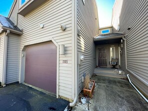 Ein zweistöckiges Haus mit Garage, Eingangstür und einer kleinen Veranda.