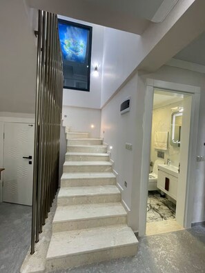 A staircase leading to a bathroom with a white toilet, sink, and mirror.