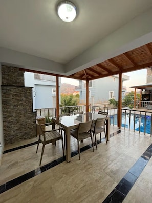 A covered outdoor area with a pool, a table with chairs, and a stone wall. - Master Vİ
4 bedroom building in phenomenal Dalaman with cool AC comfort (Muğla)