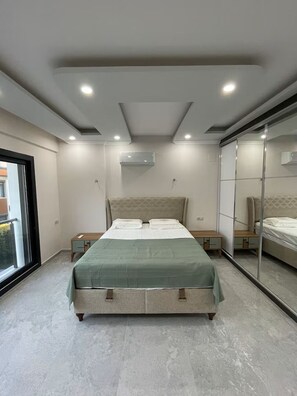 Une chambre moderne avec un lit, des tables de chevet, un miroir et un appareil de climatisation.