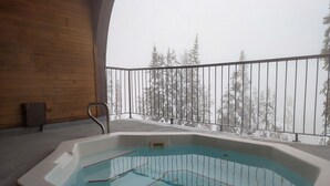 A hot tub on a balcony with a view of snow-covered trees. - Chateau on the Ridge by Okanagan Premier (Beaverdell)