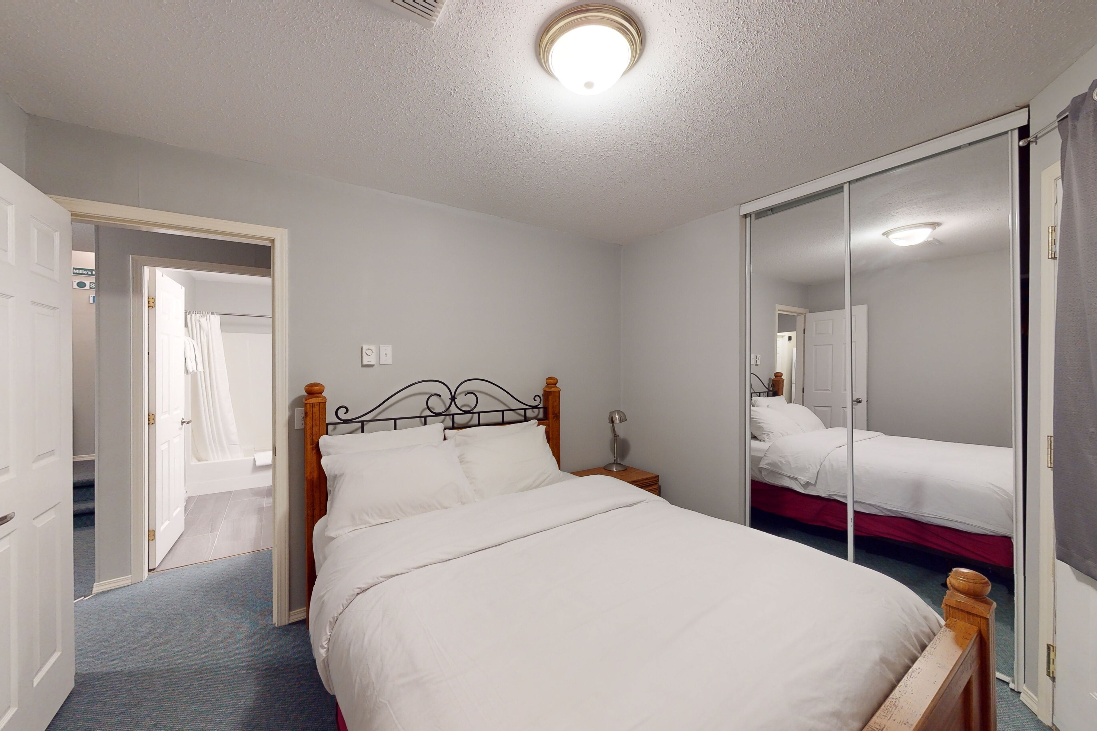 Een slaapkamer met een enkel bed, nachtkastje, spiegel en een kledingkast.