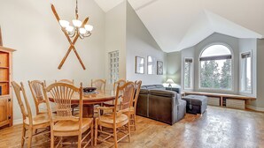 A dining area with a wooden table and chairs, a chandelier, and a bench with storage underneath. - Chateau on the Ridge by Okanagan Premier (Beaverdell)