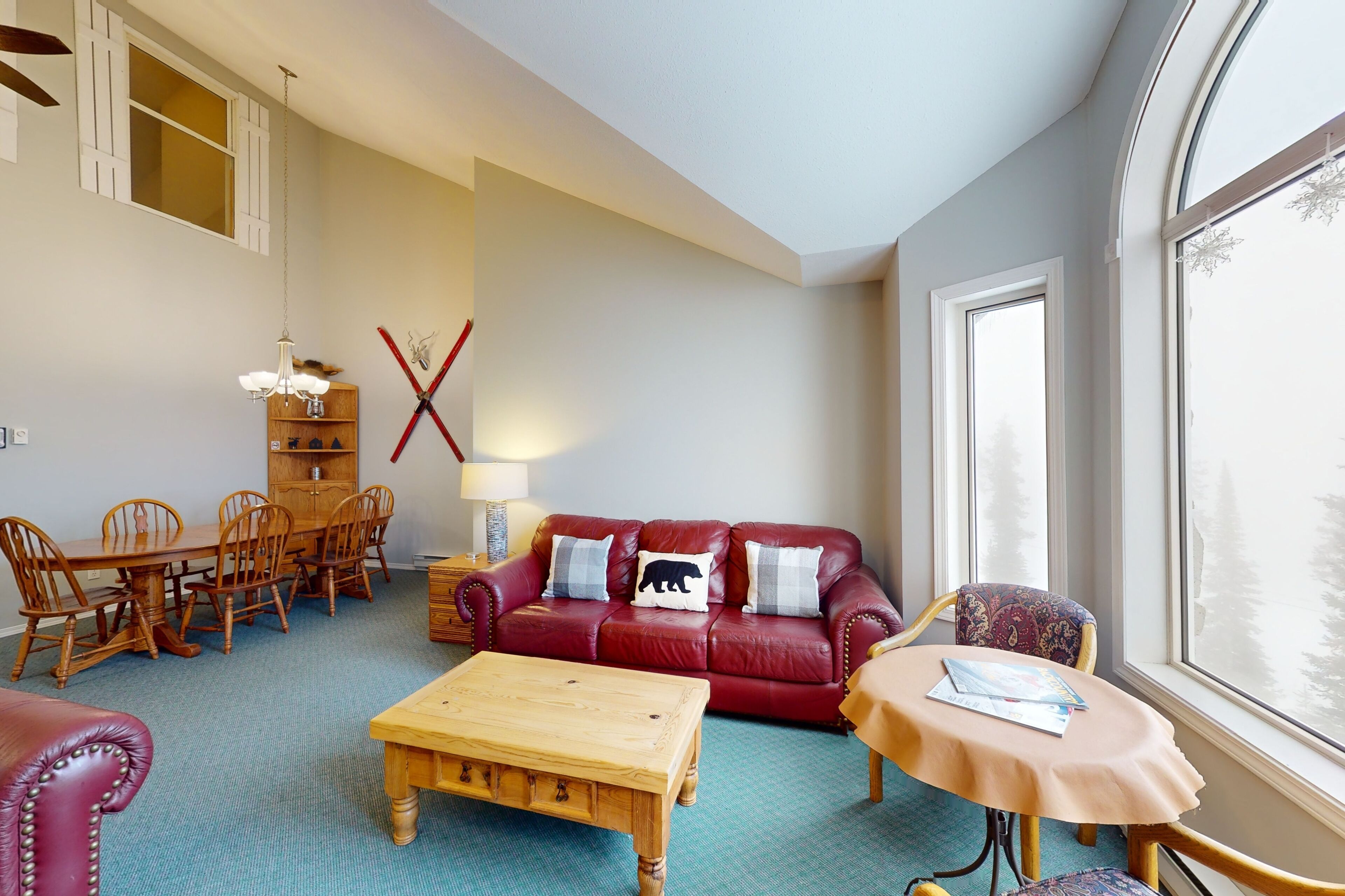 A cozy living room with a red leather sofa, wooden coffee table, and a dining area with a wooden table and chairs.